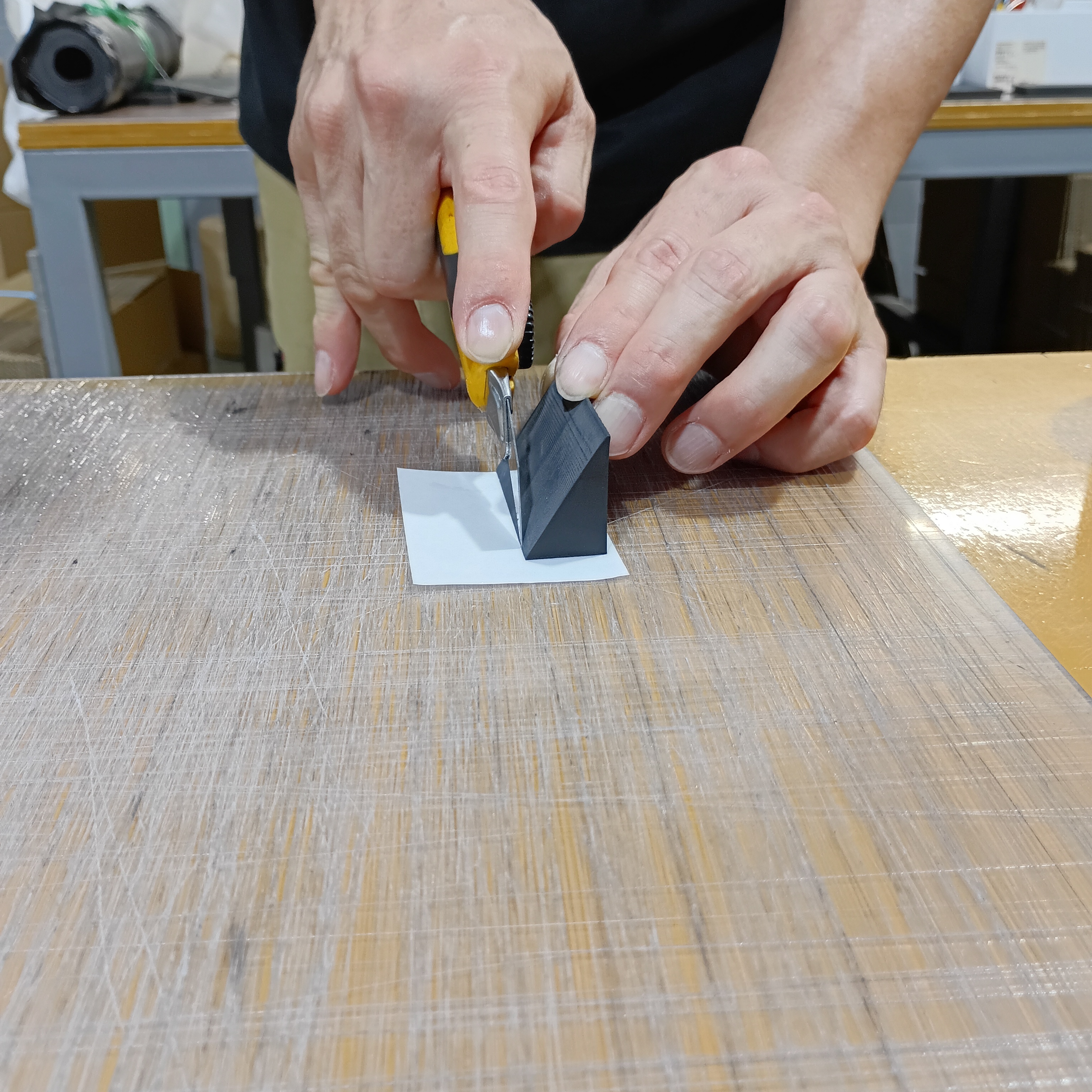 ゴム製品にカッターで両面テープを丁寧に貼り付けている職人の手元