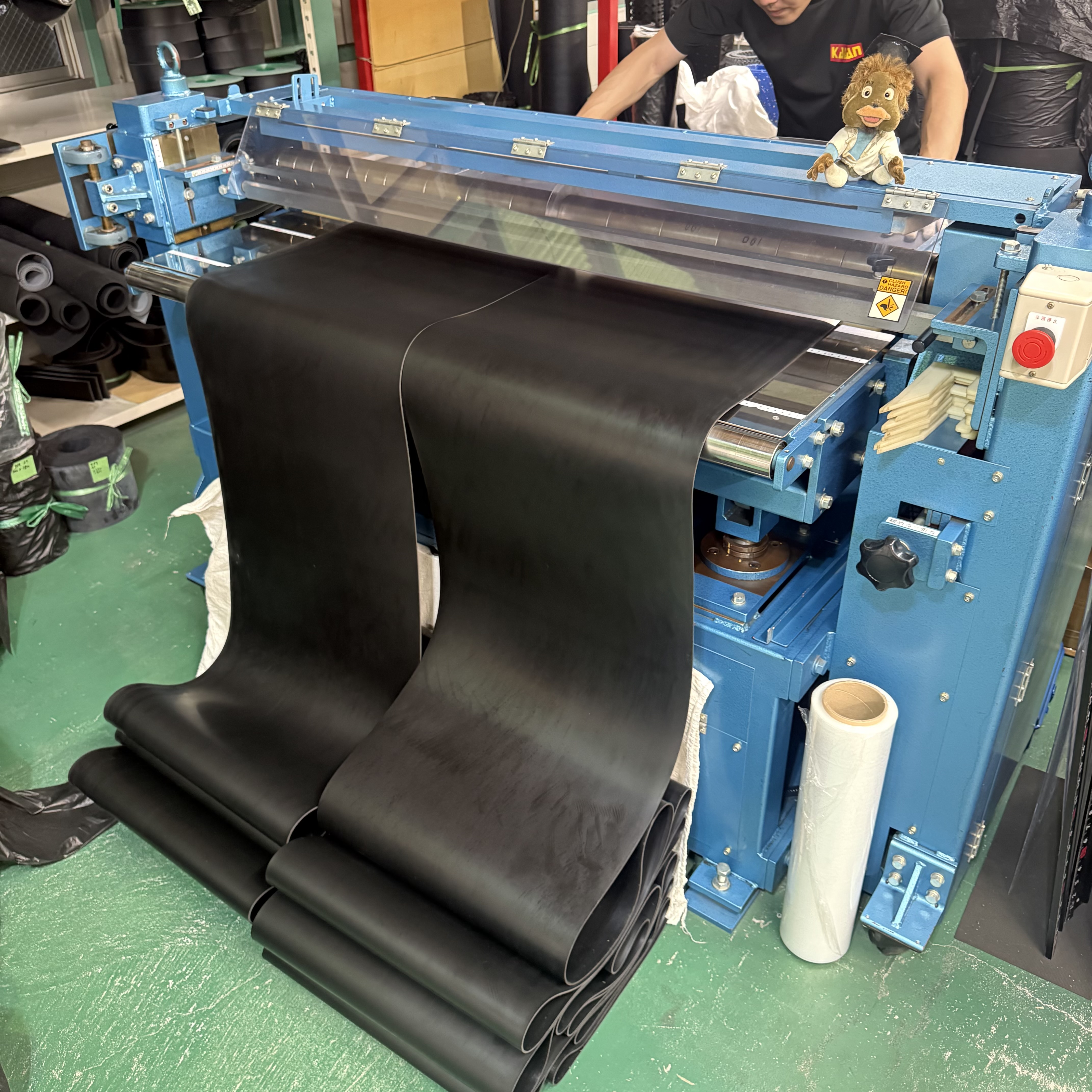 青色の幅カット専用機でゴムシートをカットしている作業風景